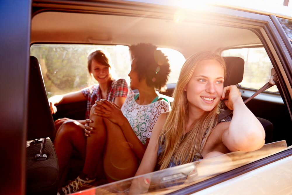 A group of young women smile in the back of their car while cruising from Seattle to Leavenworth, WA.