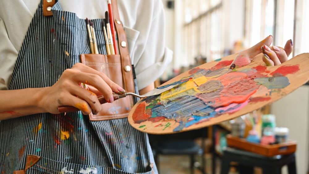 A woman is mixing paint before creating Washington State art