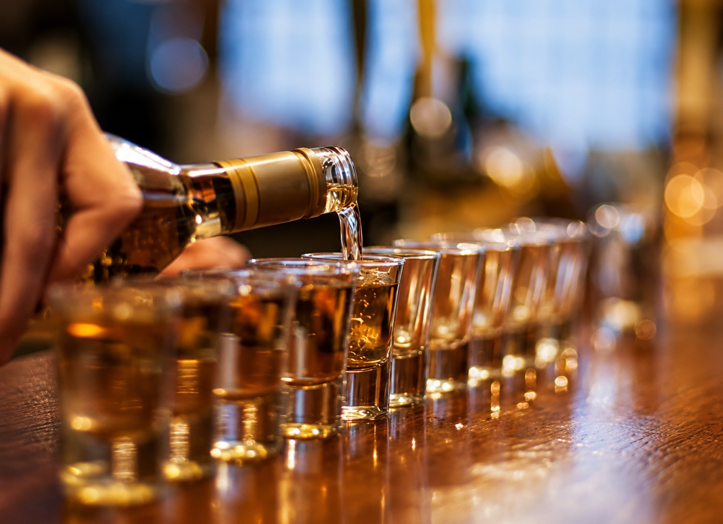 A bartender pouring a row of tasting glasses